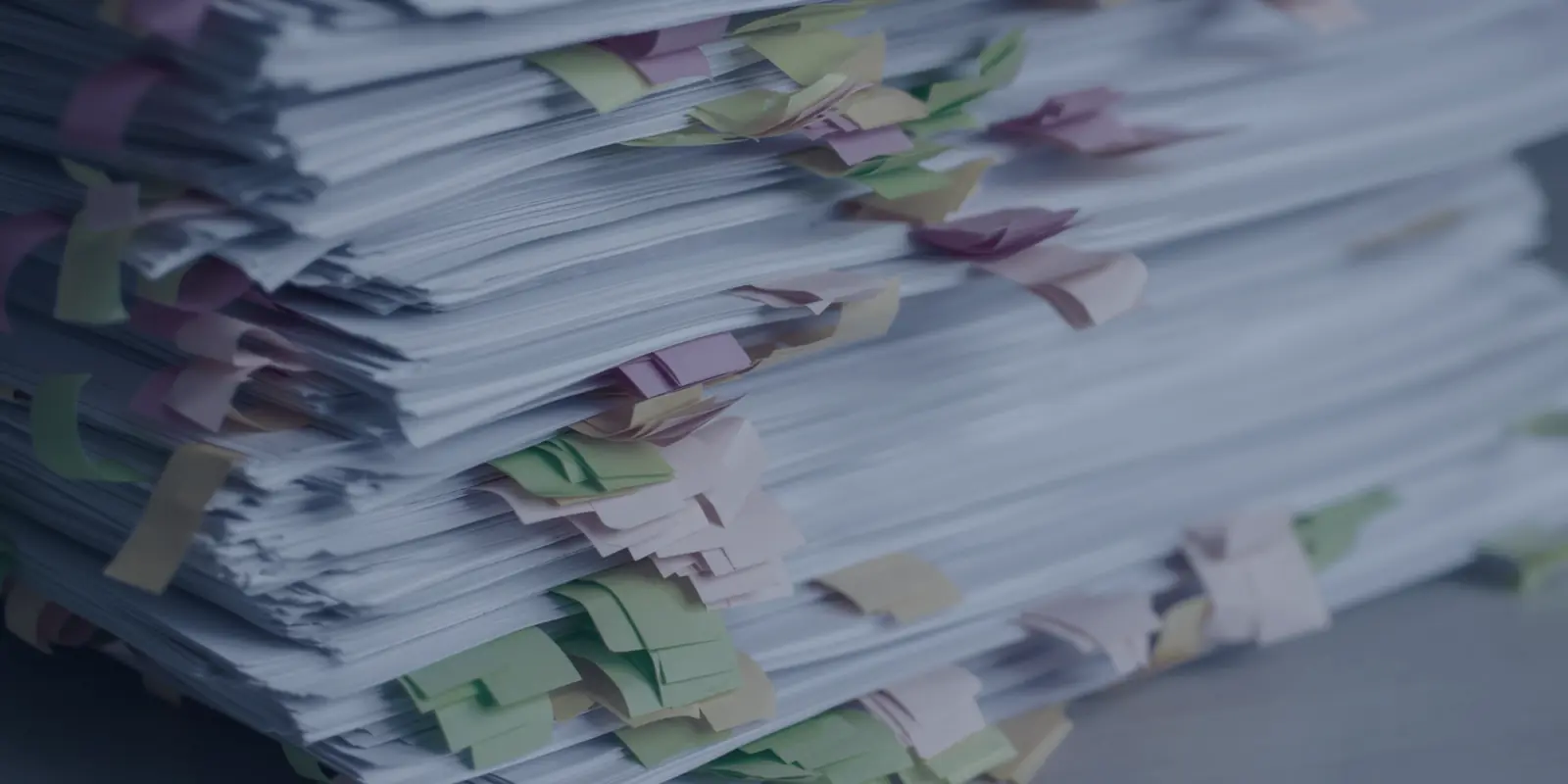 A tall stack of papers bristling with coloured sticky tabs