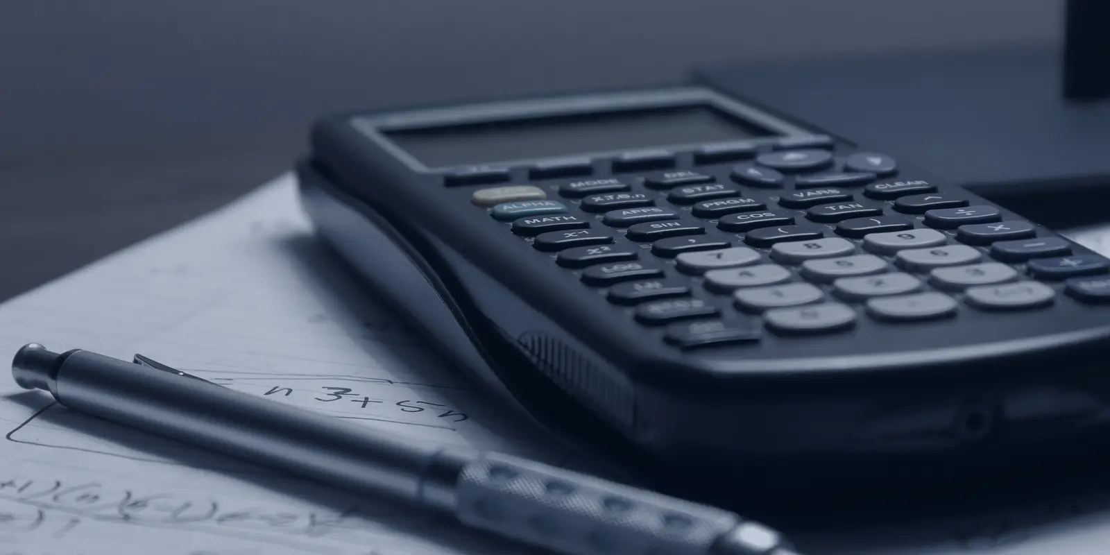 A calculator and a pen resting on handwritten notes