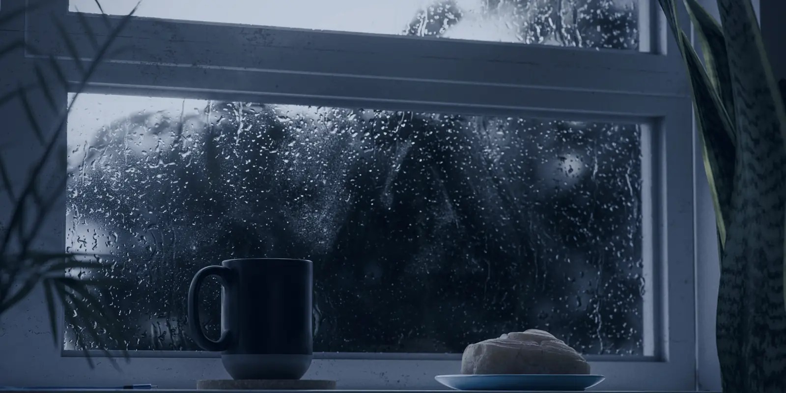 A mug of coffee and a pastry on a window sill as rain runs down the glass